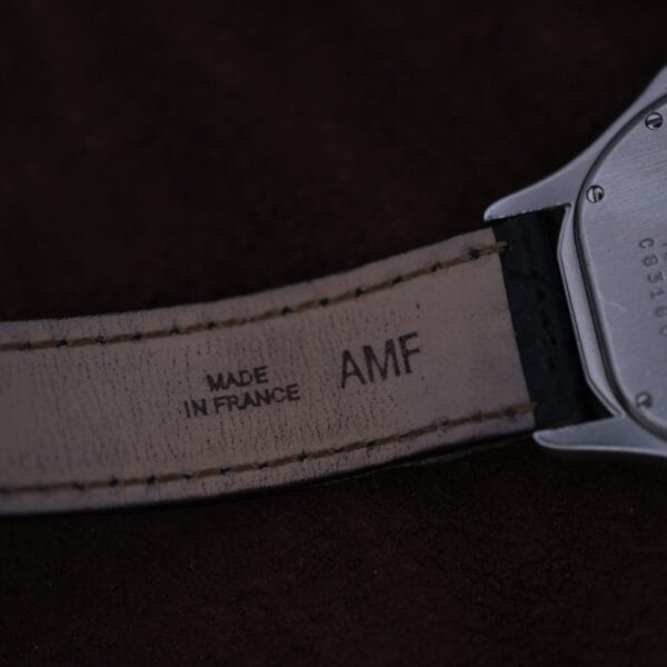 Close-up of the Cartier Cougar Gents Date Ref. 187904 strap, showing MADE IN FRANCE and AMF stamped on the leather interior near the metal case against a dark, blurred background.