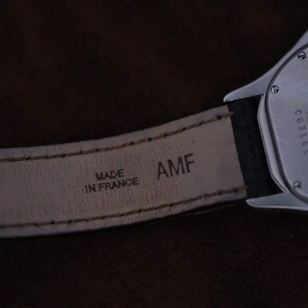 Close-up of the Cartier Cougar Gents Date Ref. 187904 strap, showing MADE IN FRANCE and AMF stamped on the leather interior near the metal case against a dark, blurred background.