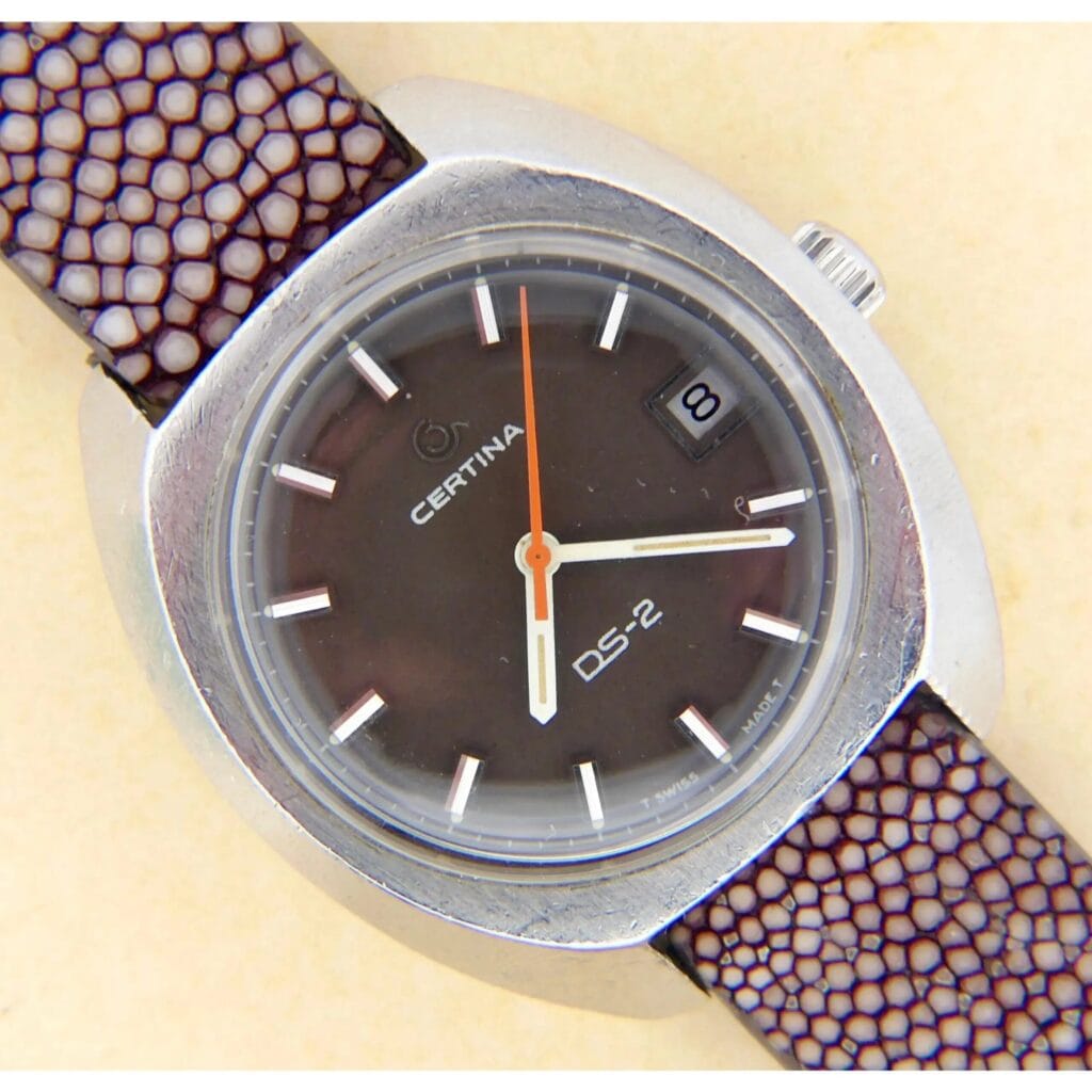 A Certina DS-2 wristwatch with a Turtle Case, black dial, orange seconds hand, and Cal. 25-661 movement.