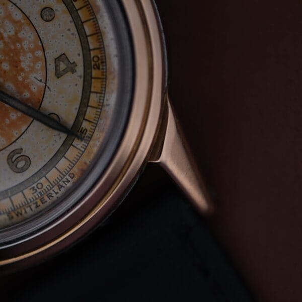 Close-up of a vintage 1945 Movado Military Dial watch featuring a darkened dial. It has a round metal case with visible hour markers and numbers 1-4 and part of 5. The text Switzerland is partially visible at the bottom.