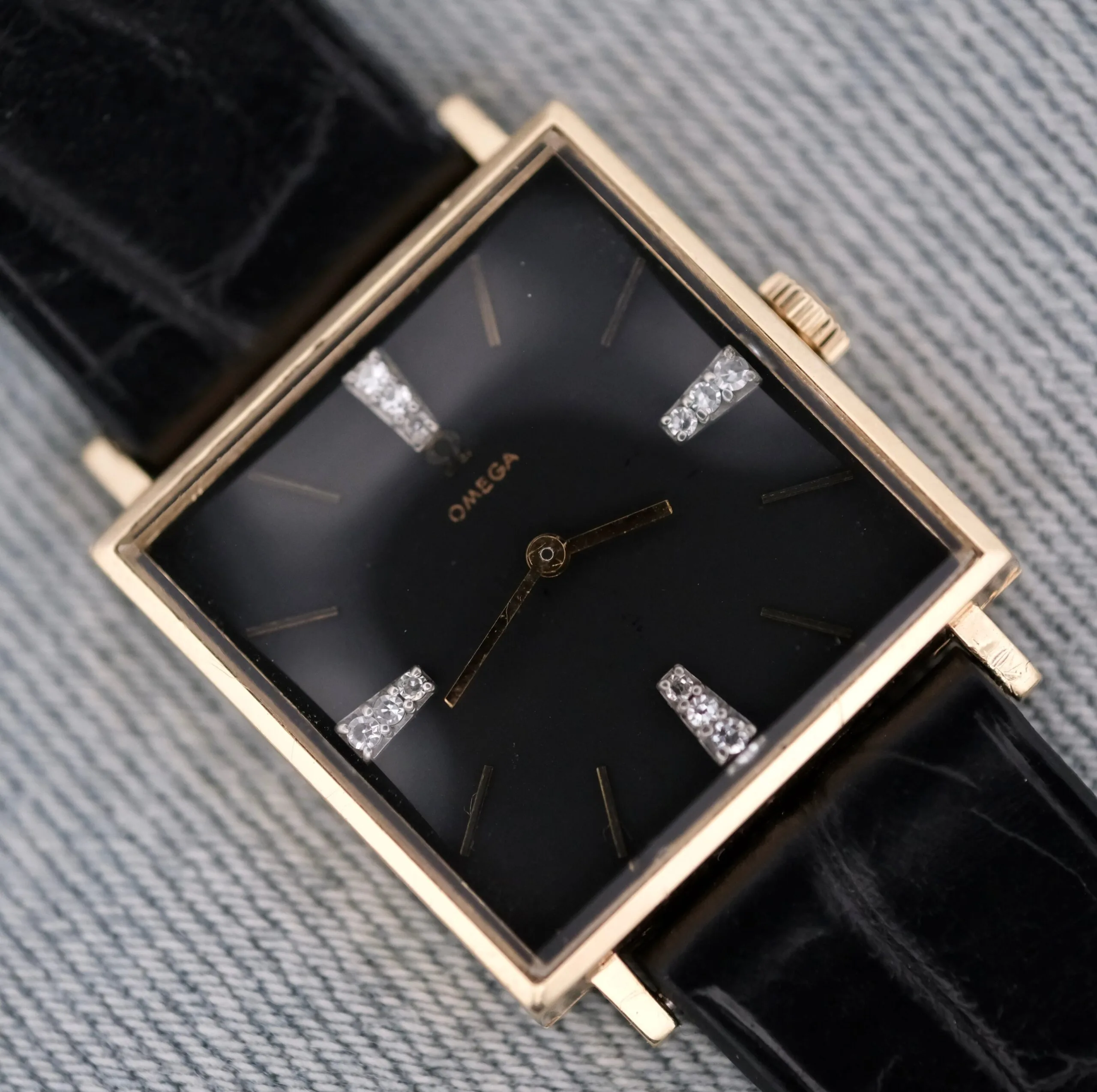 Omega 14K Square Case Diamond Markers wristwatch featuring a black face with gold details, diamond markers, and a black leather strap.
