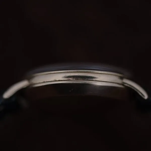 Close-up side view of the Omega Automatic Bumper Small Seconds silver case against a dark background, highlighting its curved edges and case details with strap ends partially visible.