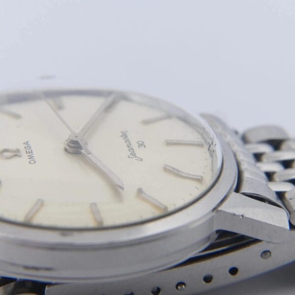 Close-up of an Omega Seamaster 30 Cal. 286 Ref. 135003 wristwatch with a silver metal bracelet, light face, and thin hour markers. The image highlights the side view, focusing on the case and bracelet details.