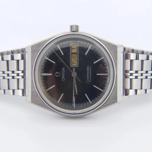 The Omega Seamaster Automatic Ref 166.210 Tropic Dial is a stainless steel wristwatch with a black dial, silver hour markers, day-date display (TUE 1), metal link band, and a timeless, classic design.