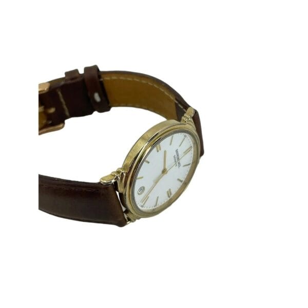 The Raymond Weil 5531 mens Swiss quartz watch features a gold-tone case, white face with gold hour markers and slender hands. It has a brown leather strap, shown with an open clasp against a white background.