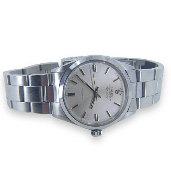 The Rolex Air King Precision 5500 is a mens stainless steel wristwatch with a silver dial and minimalist hour markers. It features a metal link bracelet, centered winding crown, sleek hour and minute hands, and a subtle second hand.