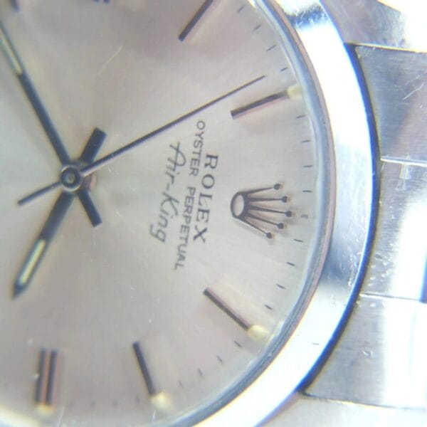 Close-up of a Rolex Air King Precision 5500 watch face, showcasing Rolex Oyster Perpetual Air-King and crown logo. It features a silver dial, metallic strap, simple hour markers, and visible hour and minute hands.