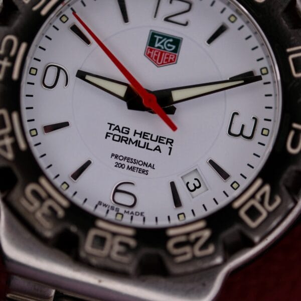 Close-up of a Tag Heuer Formula 1 Stainless Steel WAC 1111-1 watch face at 6:16:22, featuring a white dial, black numbers, metallic bezel, visible brand logo, and date window at the 3 o’clock position.