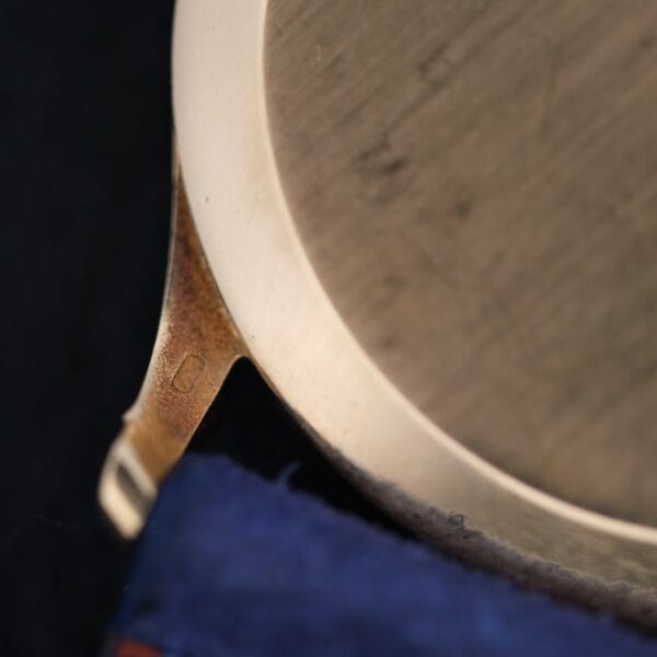 Close-up of the back and lug of a Vacheron Constantin V453 Calatrava 18k Gold - 1950s 34mm VC wristwatch case, showing slight tarnish and a small engraved mark near the lug. The background is blurred.