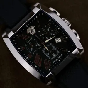 A close-up of the Versace Character Tonneau Swiss Made Chronograph, featuring a black tonneau case, textured strap, Roman numerals, and a date display.