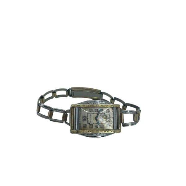 The Vintage 1932 Bulova Sky King Watch features a rectangular face with Arabic numerals and two hands, a silver geometric link band, and shows wear. The time displayed is around 10:10. It has a 14k GF case and 10AN caliber movement in a two-tone finish.
