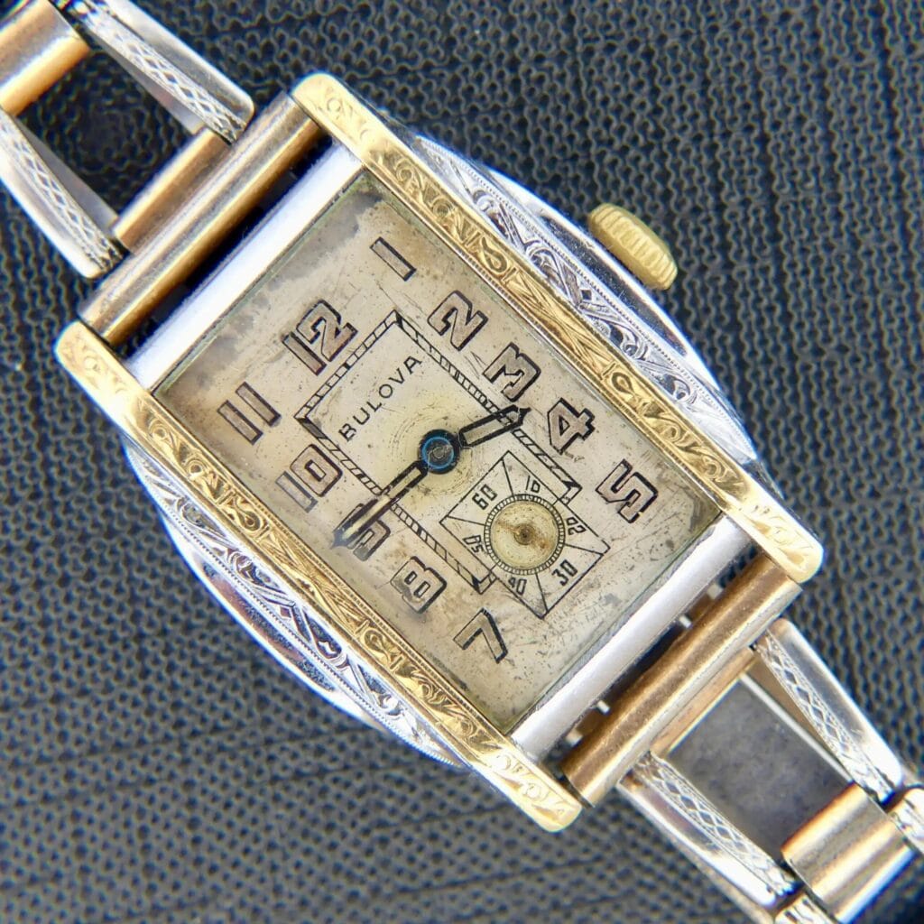 Vintage 1932 Bulova Sky King Watch with a 14k gold-filled case and two-tone band, featuring the 10AN caliber, displayed on a textured gray background.