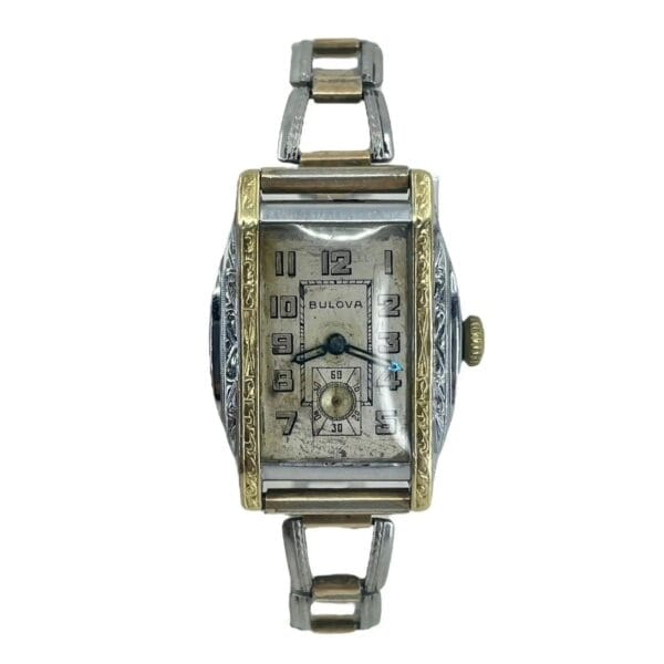 A rectangular Vintage 1932 Bulova Sky King wristwatch with a gold-tone and silver-tone metal band, featuring Arabic numerals, a small subdial above the 6 oclock position, and decorative engravings on the case.