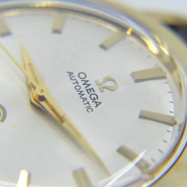 Close-up of the Vintage Omega Continental watch face, showcasing gold hands and markers. OMEGA and AUTOMATIC with the Omega logo are printed on it, while the hands point near 2 oclock.