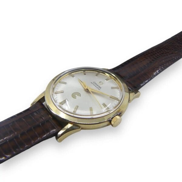 The Vintage Omega Continental Can New Old Stock Men’s Watch features a gold case, white dial with thin gold markers and hands, a textured brown leather strap, and a prominent gold crown.