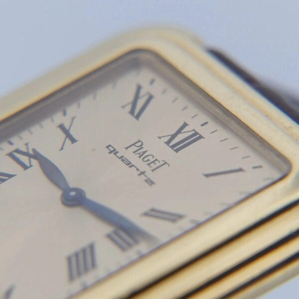Close-up of a Vintage Piaget Protocole watch with an 18k gold rectangular face, displaying Roman numerals and the word Quartz, while the hour and minute hands point to 10:09; brand name is visible above center, showcasing a classic and elegant design.