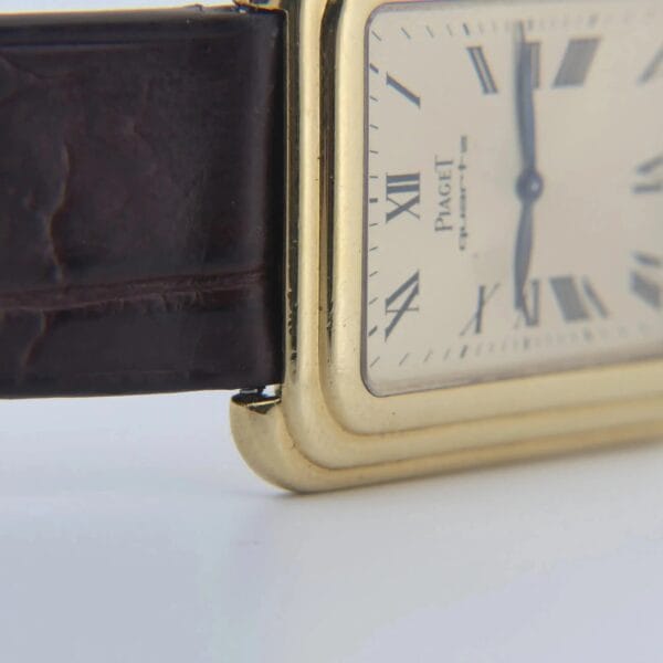 Close-up of the Vintage Piaget Protocole 74121 with a rectangular 18k gold stepped case and brown leather strap. The dial shows Roman numerals, black hands, and the Piaget brand name, highlighting its edge and strap attachment.