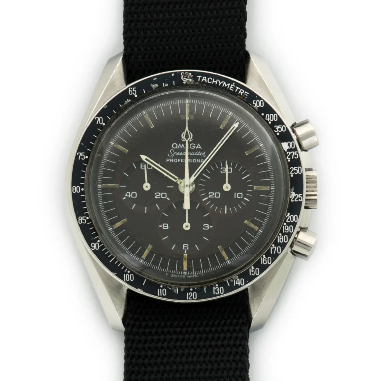 A close-up of an Omega Speedmaster 145.022 Professional wristwatch with a black dial, three subdials, white markers, and a black fabric strap. The tachymeter scale is clearly visible on the bezel.