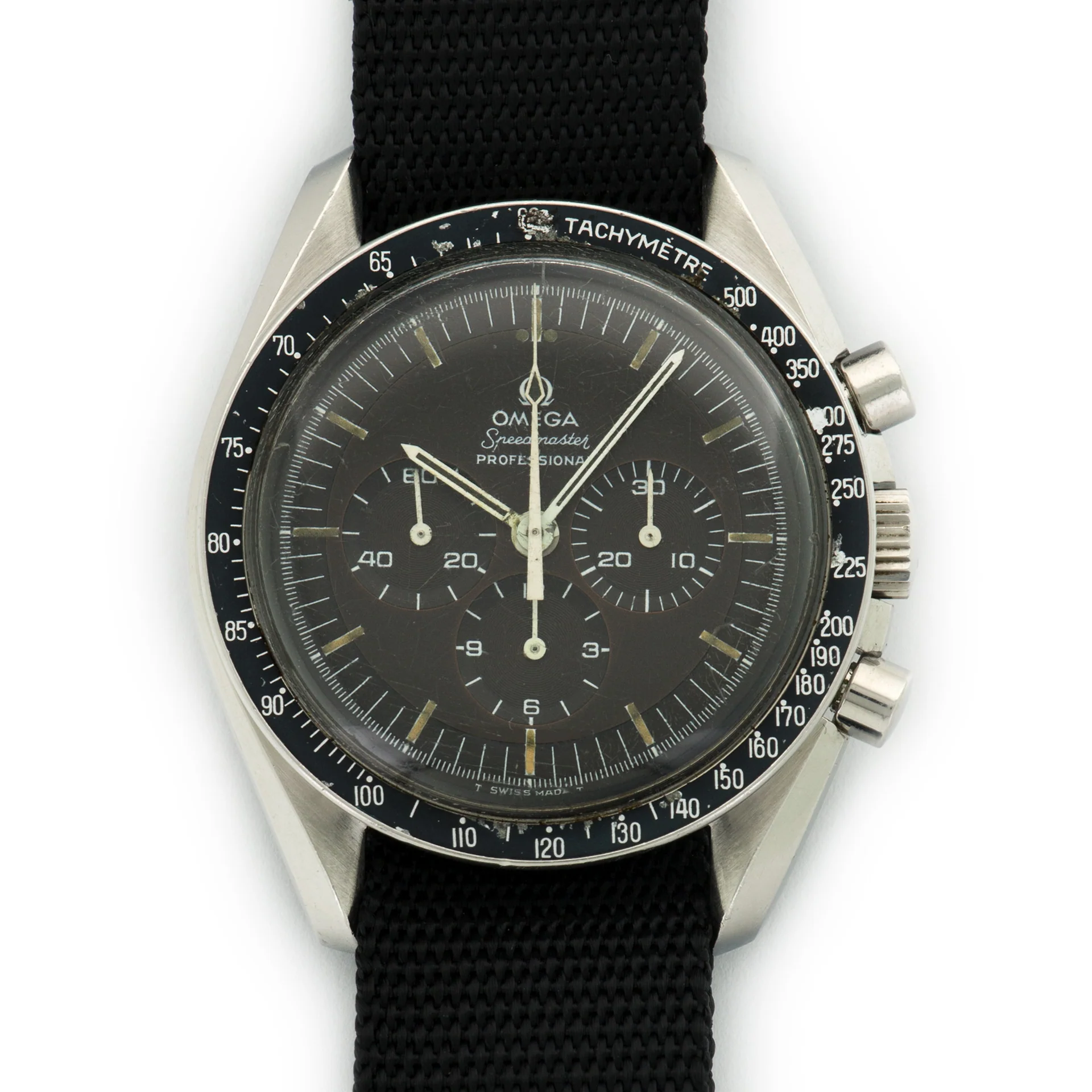 A close-up of an Omega Speedmaster 145.022 Professional wristwatch with a black dial, three subdials, white markers, and a black fabric strap. The tachymeter scale is clearly visible on the bezel.