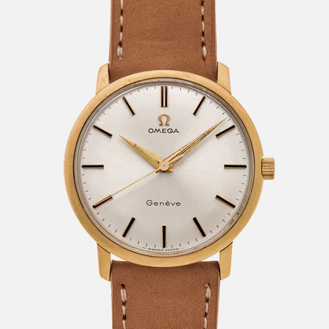 A gold Omega Geneve 131.021 wristwatch with a white face, minimalistic hour markers, and a brown leather strap. The watch displays no date and features thin black hands and the Omega logo at the top.