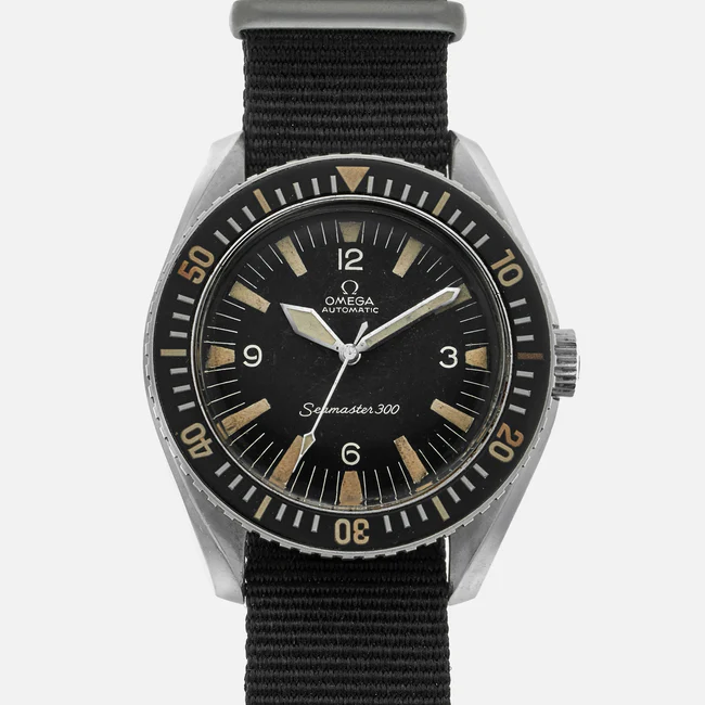 A vintage Omega Seamaster 300 165.024 wristwatch with a black dial, bold luminous hour markers, black rotating bezel, and a black fabric strap, displayed on a plain light background.