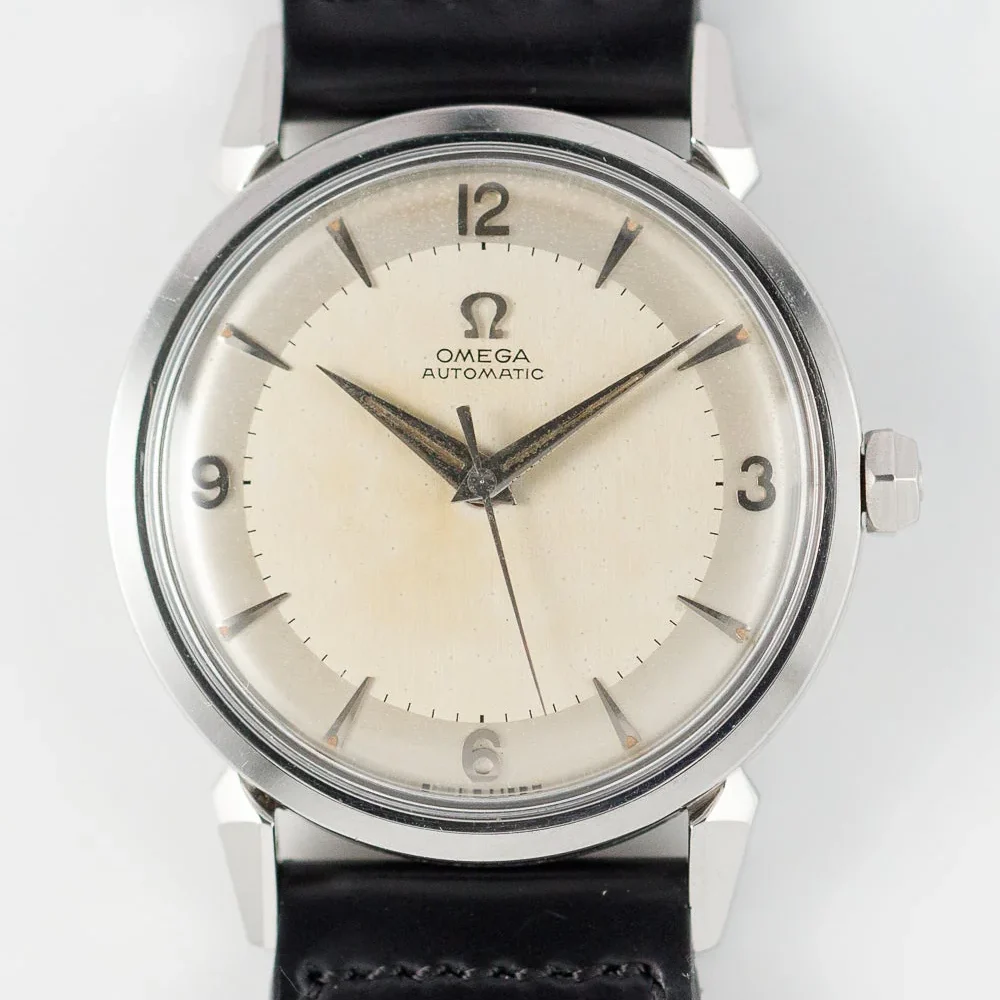 A close-up view of a vintage Omega Seamaster 2832 Automatic wristwatch with a cream-colored dial, silver hour markers, black hands, and a black leather strap. The watch features no date display and minimal branding on the face.