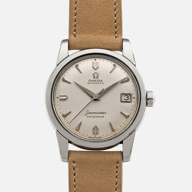 A silver Omega Seamaster Calendar 2849 wristwatch with a tan leather strap, cream dial, silver hour markers, and a date window at the 3 o’clock position, displayed on a white background.