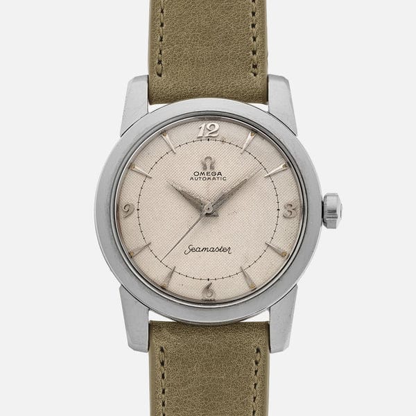 A silver Omega Seamaster 2577 wristwatch with a beige dial, numeric hour markers at 12, 3, 6, and 9, and a brown leather strap. The words Omega Automatic and Seamaster are printed on the dial.