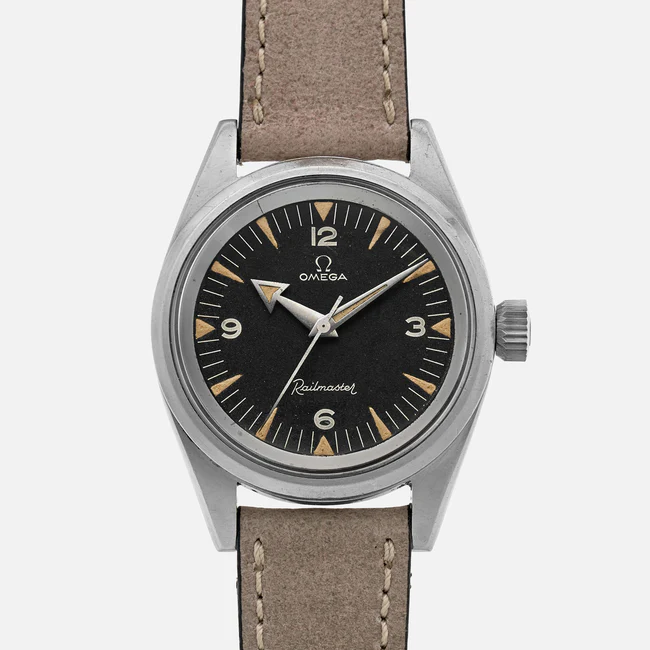 A vintage Omega Railmaster 2914 wristwatch with a black dial, white numerals, beige minute markers, and a tan leather strap. The round stainless steel case and silver hands complete this classic timepiece.