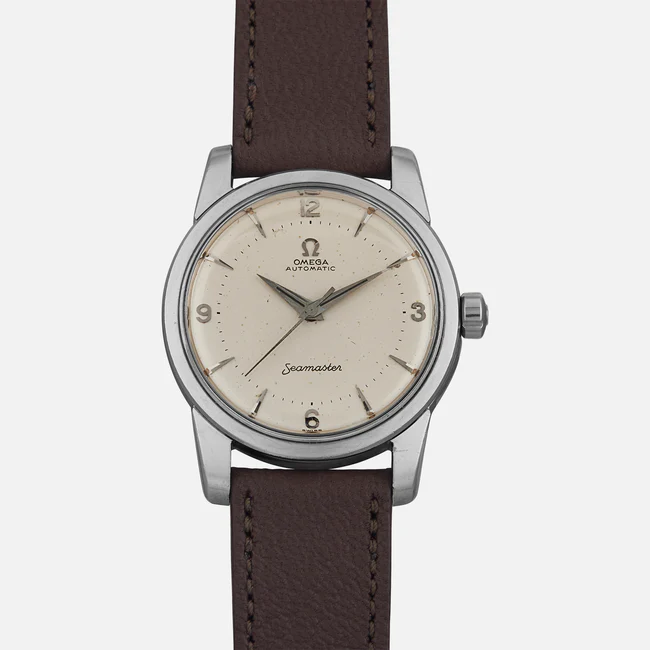 A vintage Omega Seamaster 2846 wristwatch with a cream dial, silver case, and brown leather strap. The face displays Arabic numerals at 12, 3, 6, and 9, along with the iconic Omega logo and Seamaster label.
