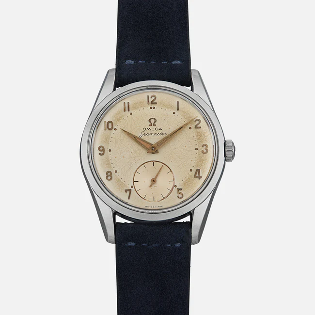 A vintage Omega Seamaster 2639 wristwatch with a cream-colored dial, Arabic numerals, small seconds subdial, silver case, and dark blue leather strap, displayed against a plain white background.