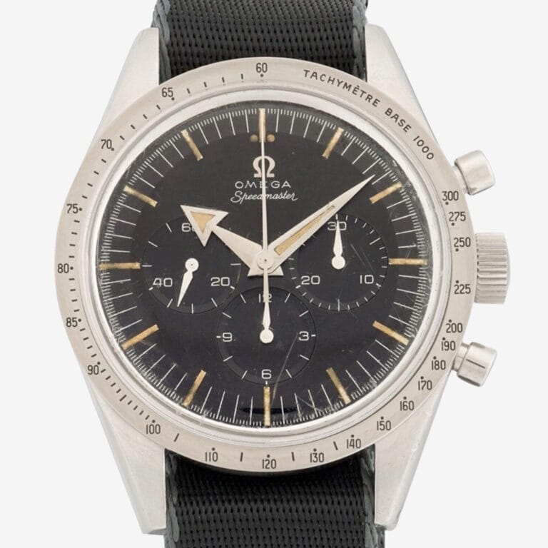 A vintage Omega Speedmaster 2915 wristwatch with a black dial, three subdials, silver hour markers, and a tachymeter scale on the bezel, shown with a black textured strap.