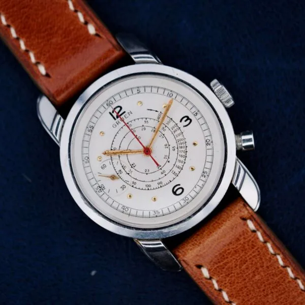 The Gruen Chronotimer Steel With Pulsations Dial features a brown leather strap and white dial with red and gold hands, showcased against a dark background.