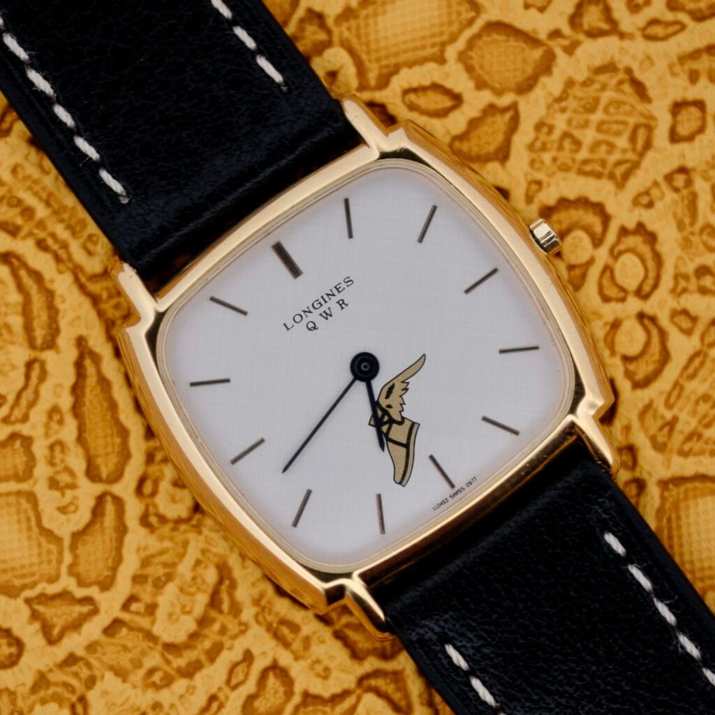 A Longines QWR For Good Year wristwatch with a white linen dial is displayed elegantly on a patterned yellow background.