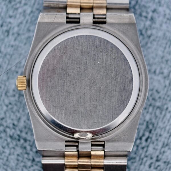 The image displays the back of an Omega Constellation Chronometer Quartz wristwatch, featuring a silver and gold metal band. The round, brushed metal back has faint engraved text at the top. The watch crown is visible on the left side.