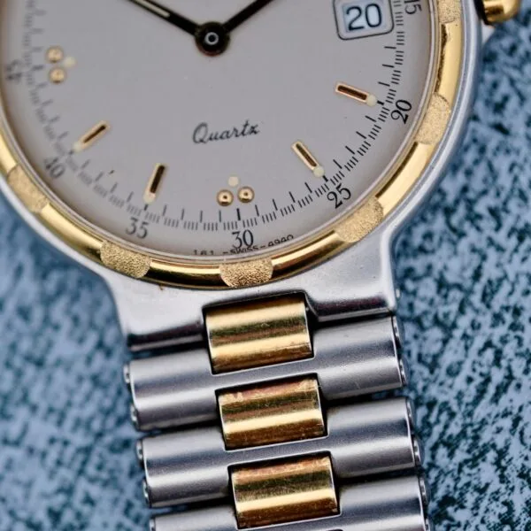 Close-up of the Longines Conquest Quartz Two-Tone 4940 wristwatch featuring a white face with gold and black markings, a date window at 3 oclock, and a silver metal band with gold links. The second hand is between 31 and 32 seconds.