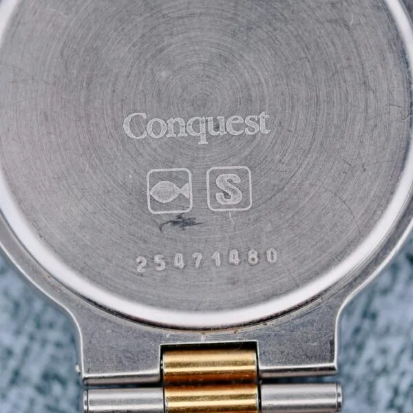 The image displays the back of a Longines Conquest Quartz Two-Tone 4940 stainless steel watch case engraved with Conquest, featuring a fish and an S in a box, with the number 25471480 beneath. A metal watch band is attached.