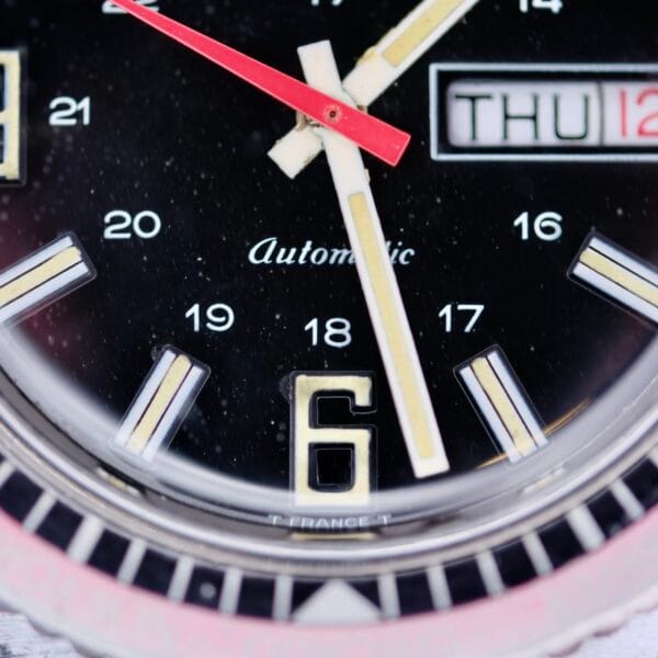 Close-up of the Clinton World Timer Automatic Day/Date watch face at 12:29:04, displaying THU 12. The number 6 is prominent at the bottom, with Automatic visible.