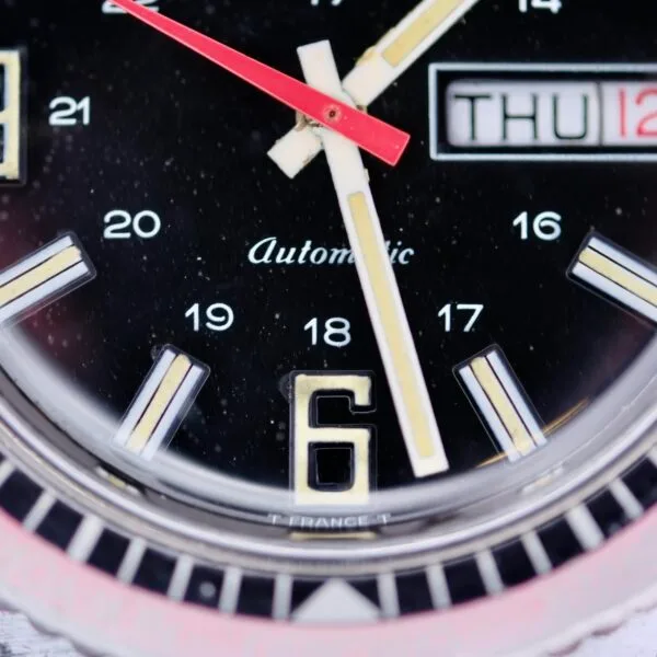 Close-up of the Clinton World Timer Automatic Day/Date watch face at 12:29:04, displaying THU 12. The number 6 is prominent at the bottom, with Automatic visible.