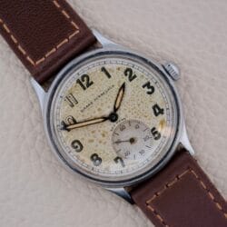 Close-up of a Girard Perregaux Sea Hawk Military Circa 1943 wristwatch featuring a brown leather strap and a speckled vintage dial, evoking classic military style.