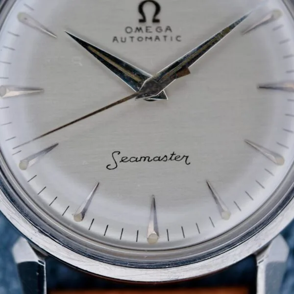 Close-up of the Omega Seamaster Automatic 2832-15 watch face, featuring silver hour markers and hands, with black text on a silver dial. The Omega logo and Seamaster are prominently displayed.