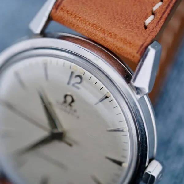 Close-up of the Omega Seamaster Automatic 2832-15 wristwatch with a brown leather strap, silver round case, black hour markers, and the Omega logo on the dial. The watch shows the time as 10:09.