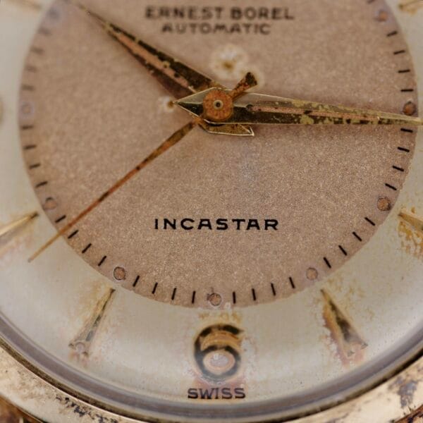 Close-up of the Ernest Borel Incastar 1560 Gold Capped watch face, displaying hour, minute, and second hands with visible wear on the dial. The words ERNEST BOREL AUTOMATIC, INCASTAR, and SWISS appear.