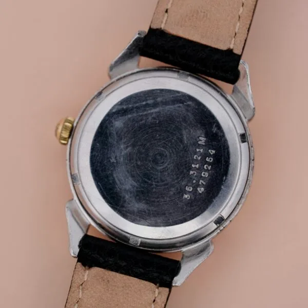 The back of an Ernest Borel Incastar 1560 Gold Capped watch features a black and beige leather strap, visible scratches, and engraved serial numbers 364314 M and 4979264 on the metal case back.