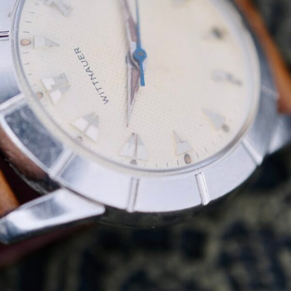 Close-up of a Wittnauer 2065 Waffle Dial with Art Deco indices, cream textured dial, triangular hour markers, silver bezel, blue hands, and a brown leather strap.