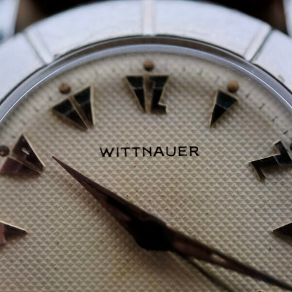 Close-up of a Wittnauer 2065 Waffle Dial watch face featuring a textured cream dial, Art Deco indices, two hands, and WITTNAUER in black lettering at the center.