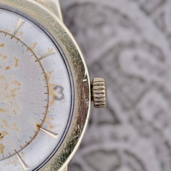 Close-up of the right side of an Omega Seamaster Automatic 2577-17 Tropic Dial wristwatch with a tarnished white face, gold-colored case, visible crown, partial number 3, and spotted, discolored dial.