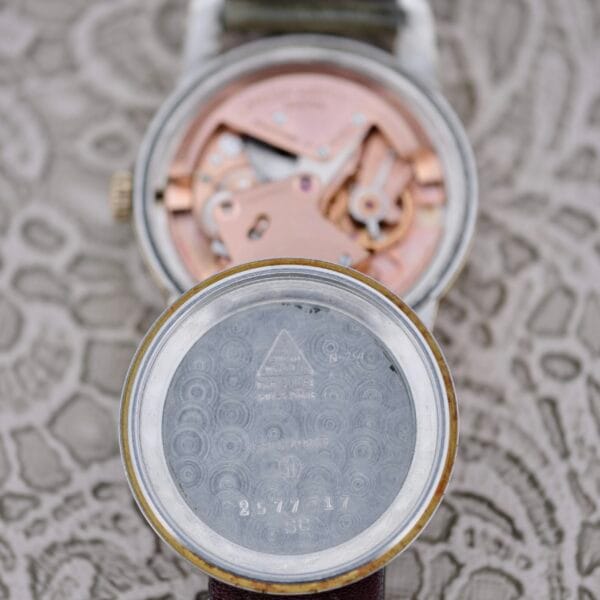 Close-up of the Omega Seamaster Automatic 2577-17 Tropic Dial wristwatch with its case back removed and placed in front, revealing the watch movement, internal components, and engraved markings inside the case back.