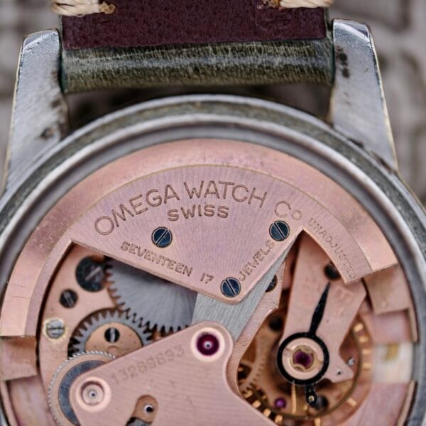 Close-up view of the internal mechanism of the Omega Seamaster Automatic 2577-17 Tropic Dial, showing gears and the engraved text OMEGA WATCH CO SWISS SEVENTEEN 17 JEWELS UNADJUSTED on its metal components.