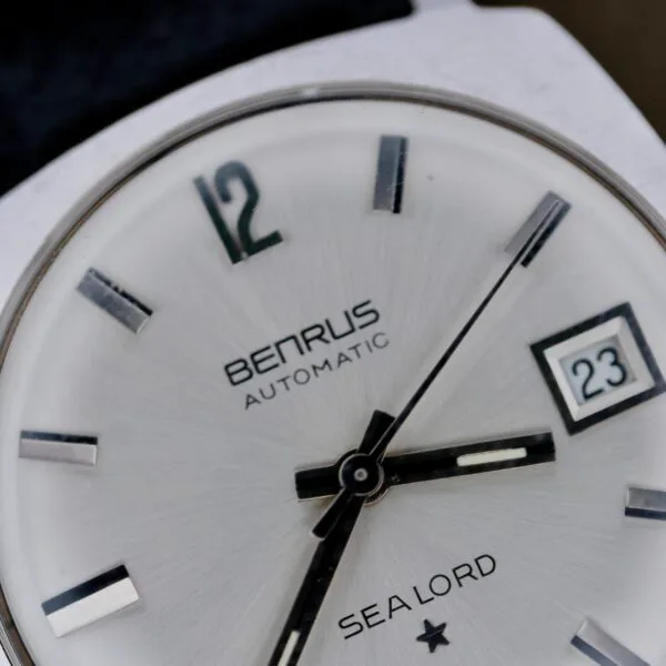 Close-up of a Benrus Automatic Sea Lord Date wristwatch, featuring black and silver hour markers, three hands showing 12:16:36, and the date set to 23.